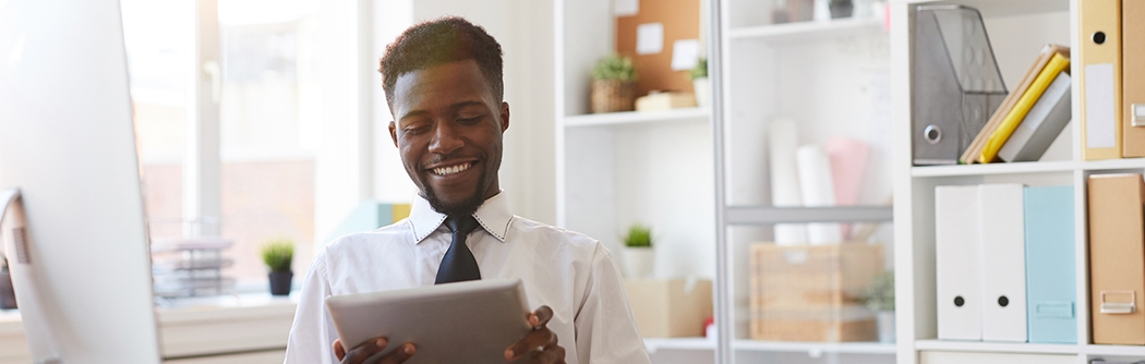 Young businessman with tablet sitting at desk in office.