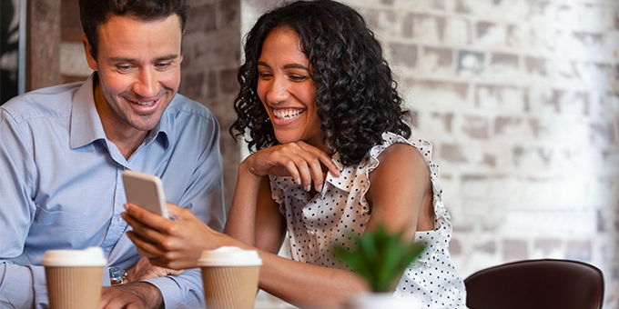 Couple in coffee shop looking at cell phone.