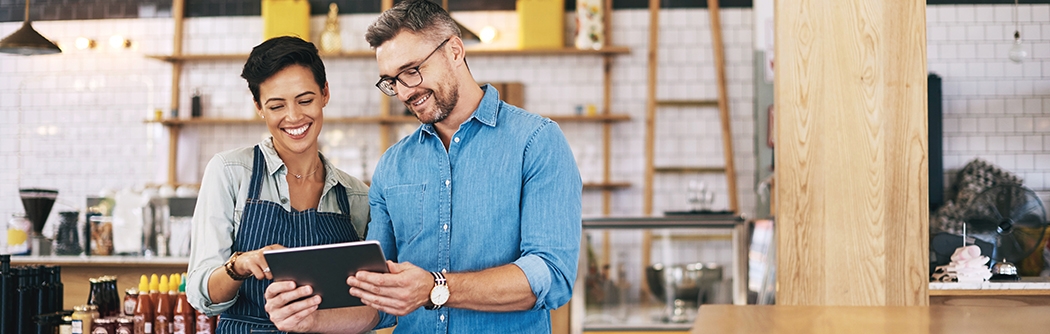 Coworkers using a digital tablet in a coffee shop.