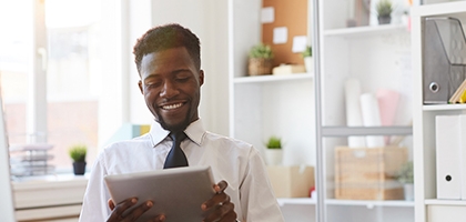 Young businessman with tablet sitting at desk in office.