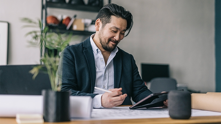 A businessman at his desk working on a tablet.