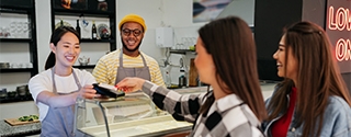 Women making a credit card tap payment at a shop counter.