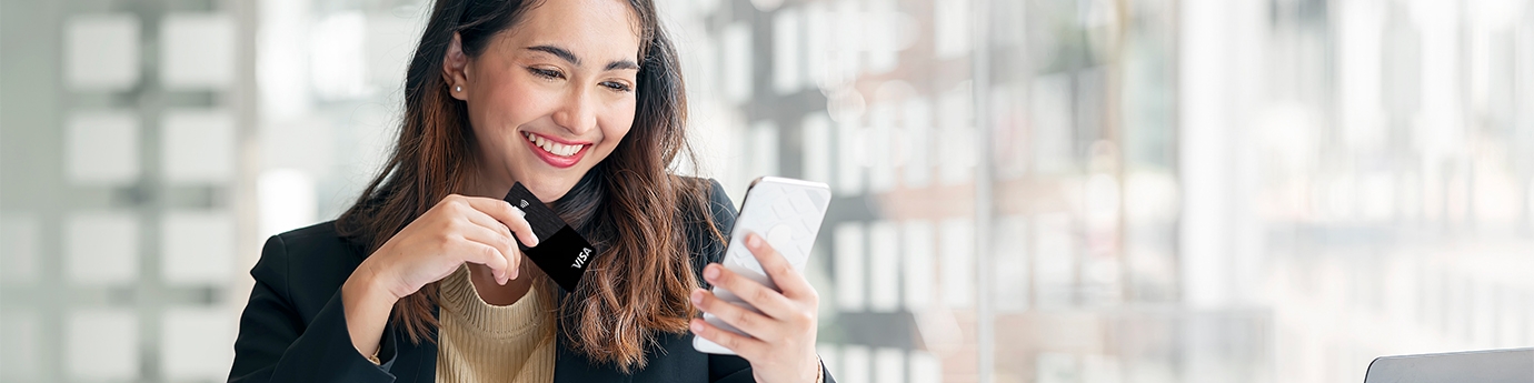 Businesswoman holding WaFd Bank Commercial credit card making a mobile purchase.