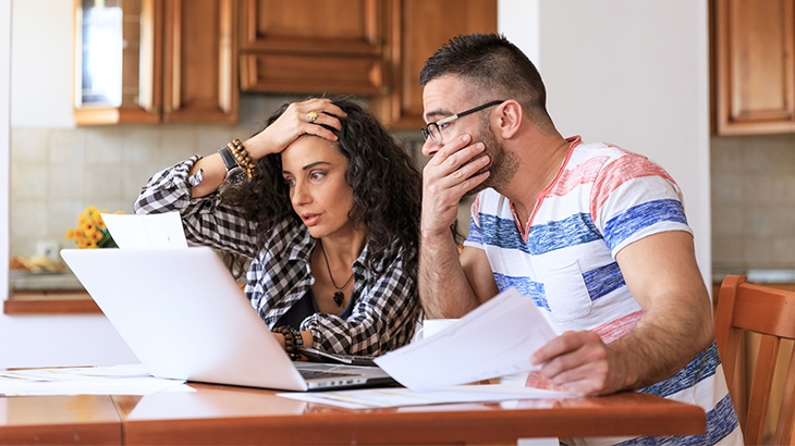 Couple sitting at table stressed looking at bills