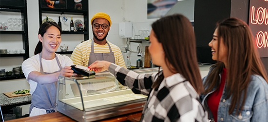 Women making a credit card tap payment at a shop counter.