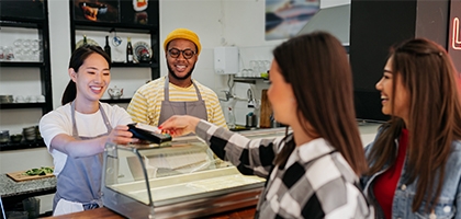 Women making a credit card tap payment at a shop counter.