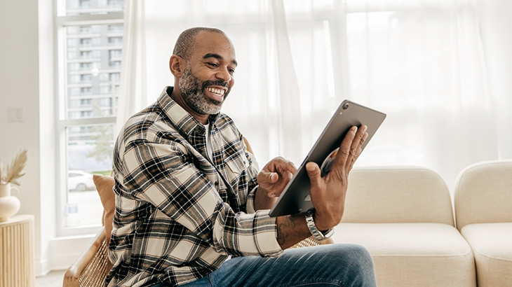 Man sitting in living room using a tablet.