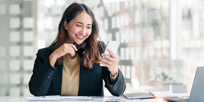 Businesswoman holding WaFd Bank Commercial credit card making a mobile purchase.