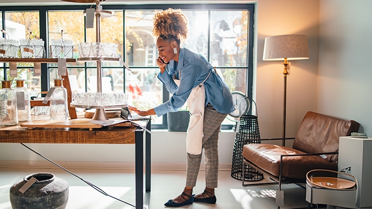 Businesswoman typing order while on phone with a client.