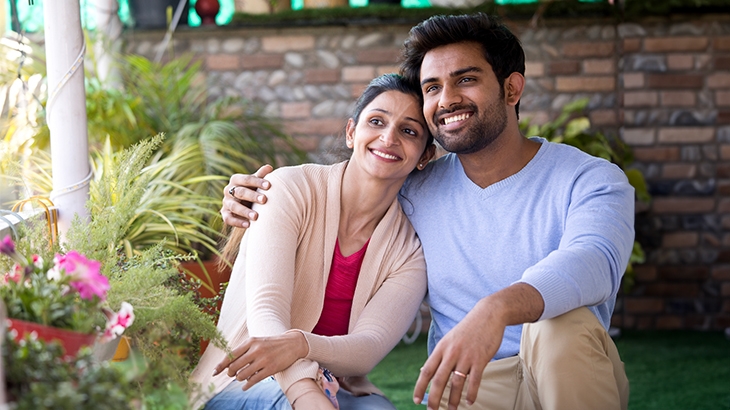 Happy couple sitting on porch by plants