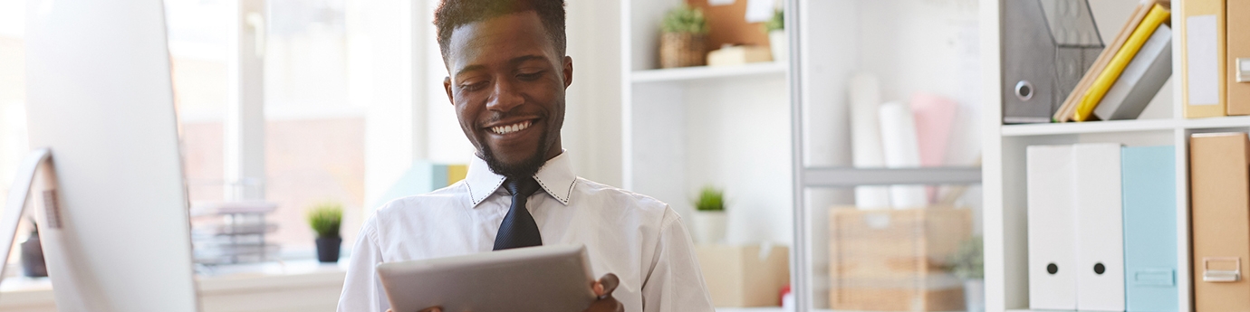 Young businessman with tablet sitting at desk in office.