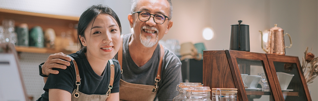Padre e hija manejando en su cafetería, sonriendo en el mostrador.