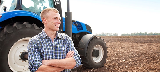 Farmer standing in front of a tractor.