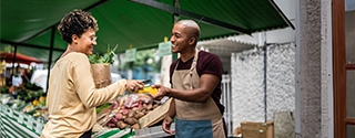 Woman checking out at vegetable stand with a mobile phone.