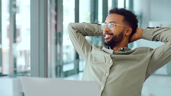 Businessman relaxing at his desk with hands behind head.