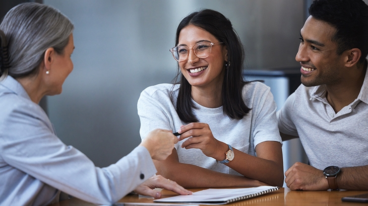 Couple taking pen from consultant to sign paperwork