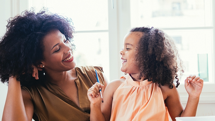 Mother and daughter smiling at each-other while painting