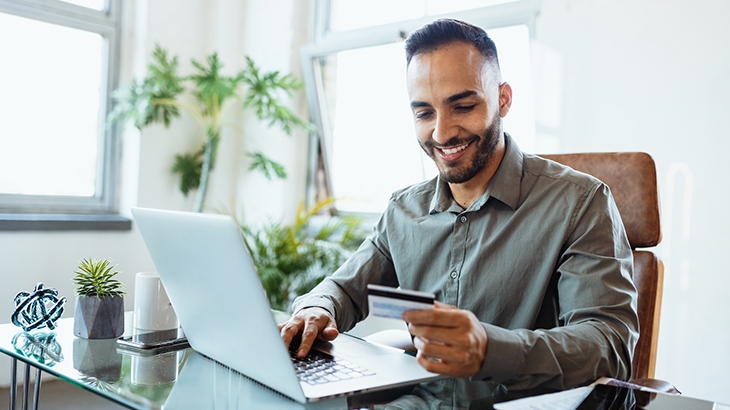 Businessman working on laptop and making online credit card purchase.