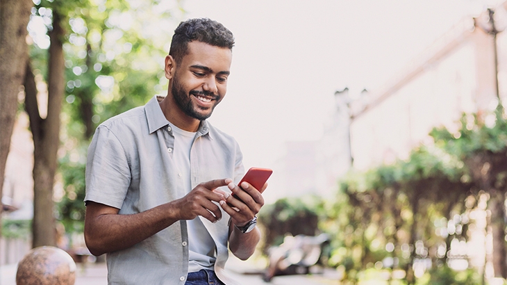 Man using a smartphone outside in a park.