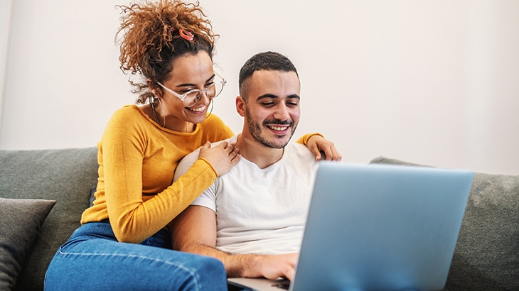 Couple sitting at home and using laptop.