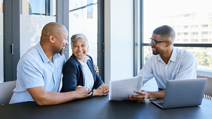 Mature couple smiling while going over savings account options with financial advisor