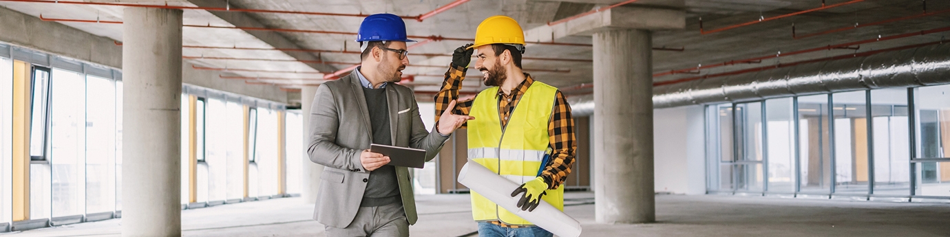 Construction worker and architect talking in building under construction.