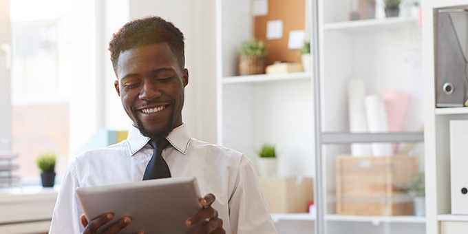 Young businessman with tablet sitting at desk in office.