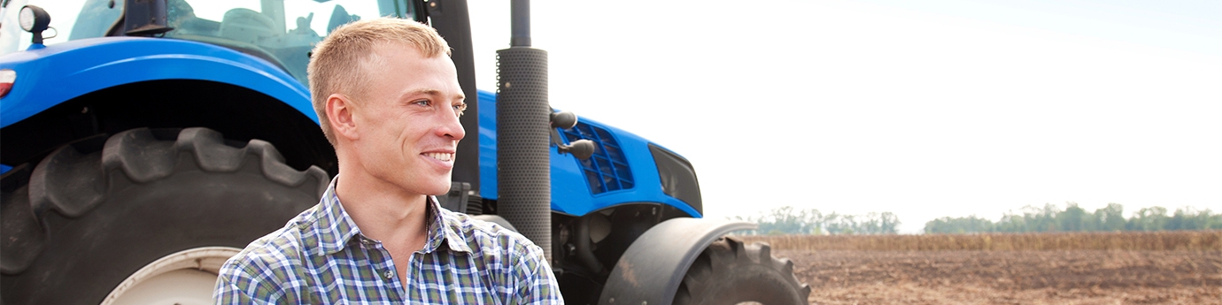 Farmer standing in front of a tractor.