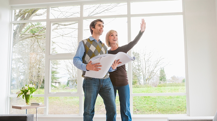 Couple holding building plans and discussing home remodel