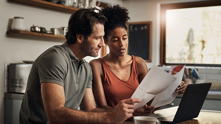 Couple reviewing papers and working on a laptop.