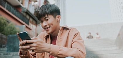 Man sitting on stairs outside using his smartphone.