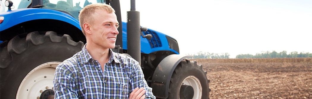 Farmer standing in front of a tractor.