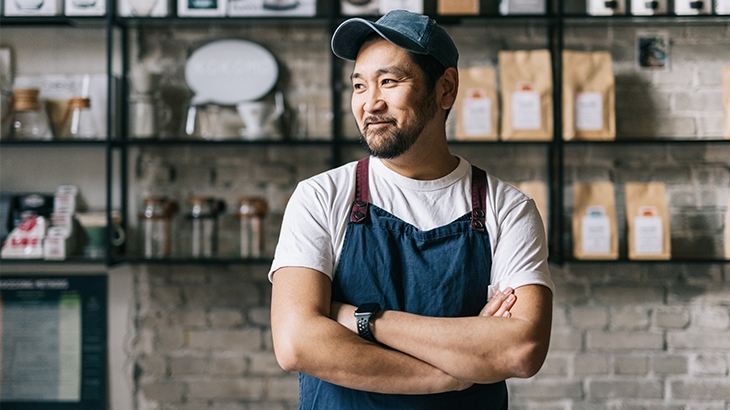 Coffee shop owner smiling while in his shop.