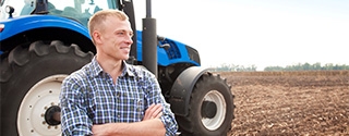 Farmer standing in front of a tractor.