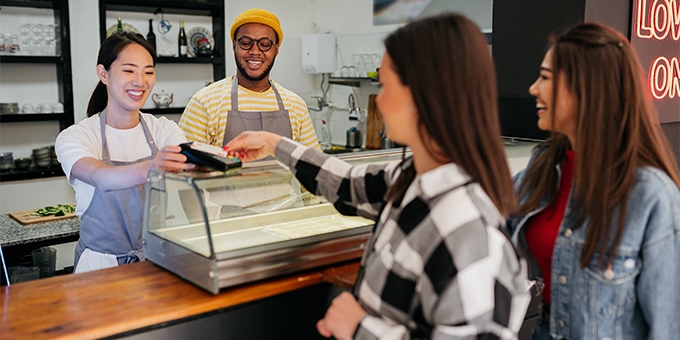 Women making a credit card tap payment at a shop counter.