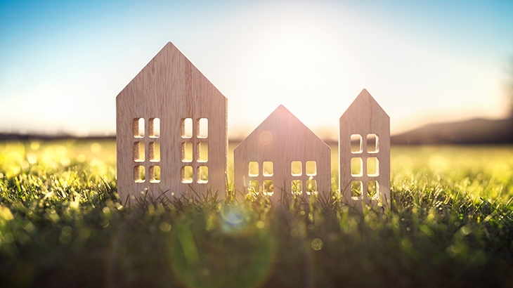 Wood model house in empty field at sunset.