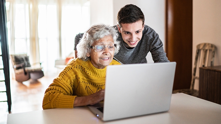 Grandson and Grandmother using laptop at home.