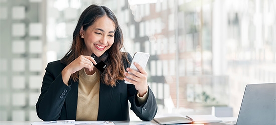 Businesswoman holding WaFd Bank Commercial credit card making a mobile purchase.