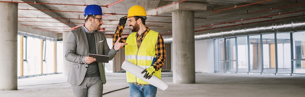 Construction worker and architect talking in building under construction.