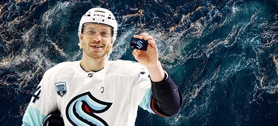 Hockey player holding a WaFd Seattle Kraken debit card.