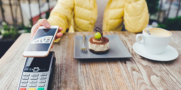 Woman paying for dessert with digital debit card mobile pay